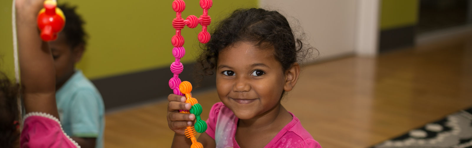 An image of a smiling young girl playing with toys at a Benevolent Society Early Years Centre 